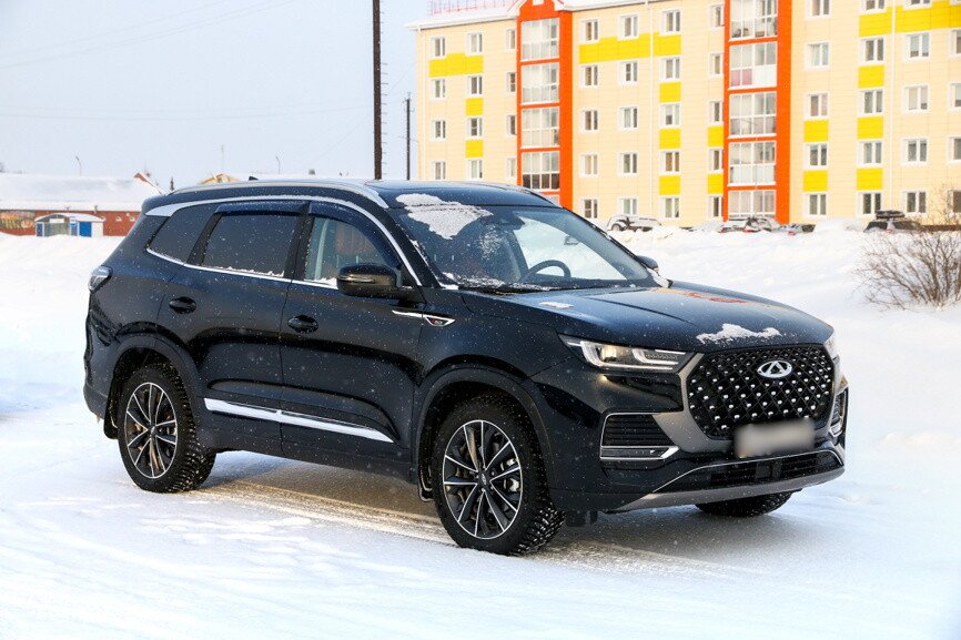 Припаркованный Chery Tiggo 8 Pro Max черного цвета, зимний двор многоквартирного дома