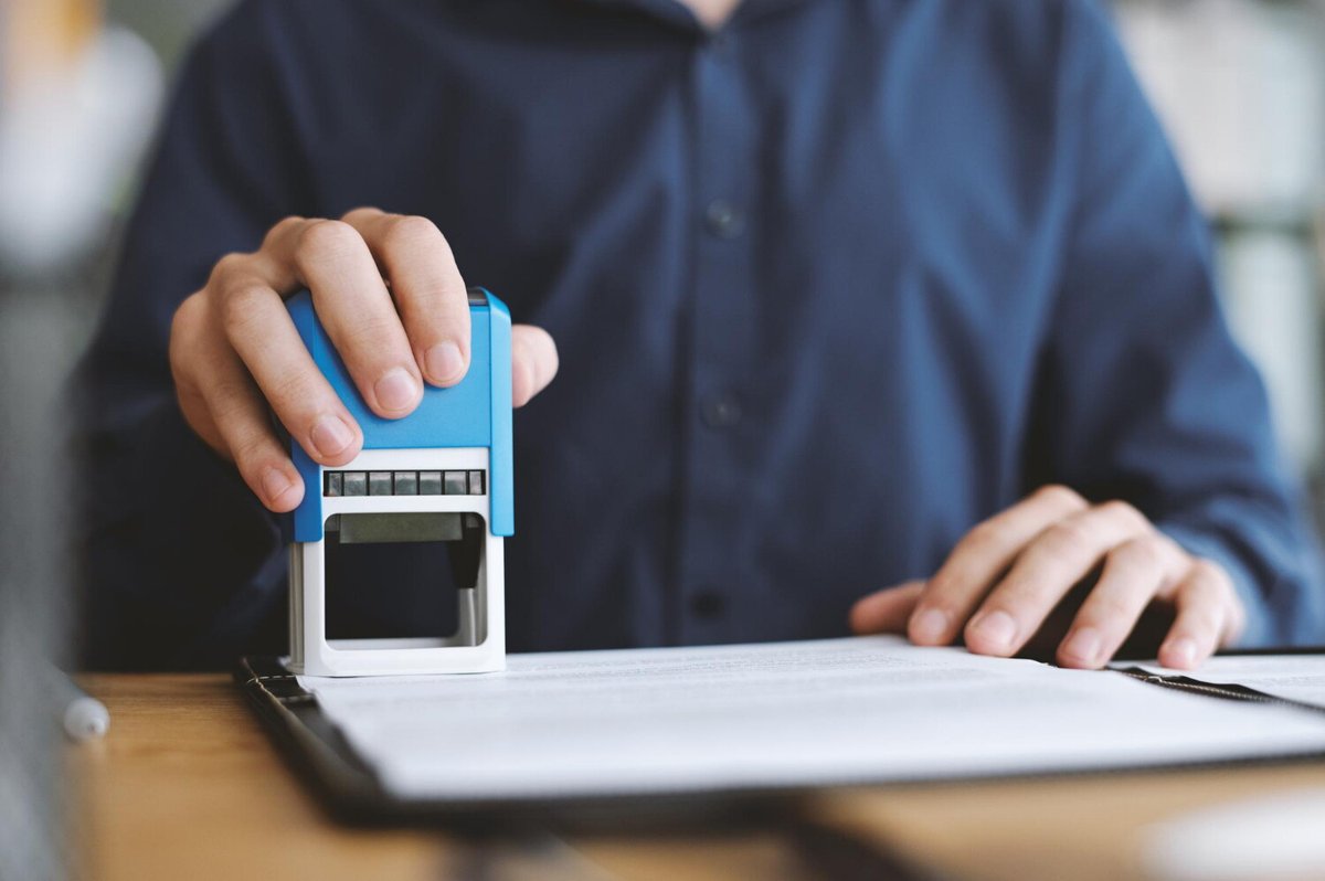 Мужчина ставить печать на документ