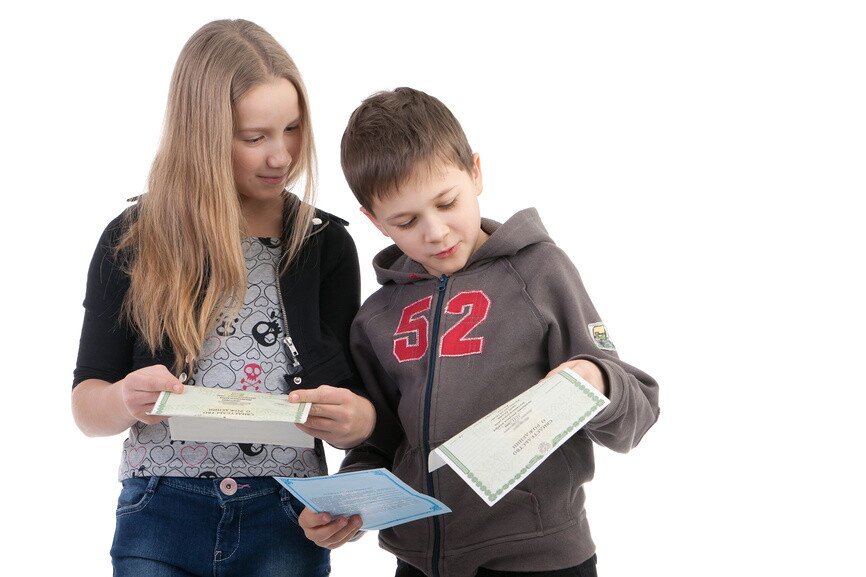 Девочка и мальчик рассматривают свои свидетельства о рождении