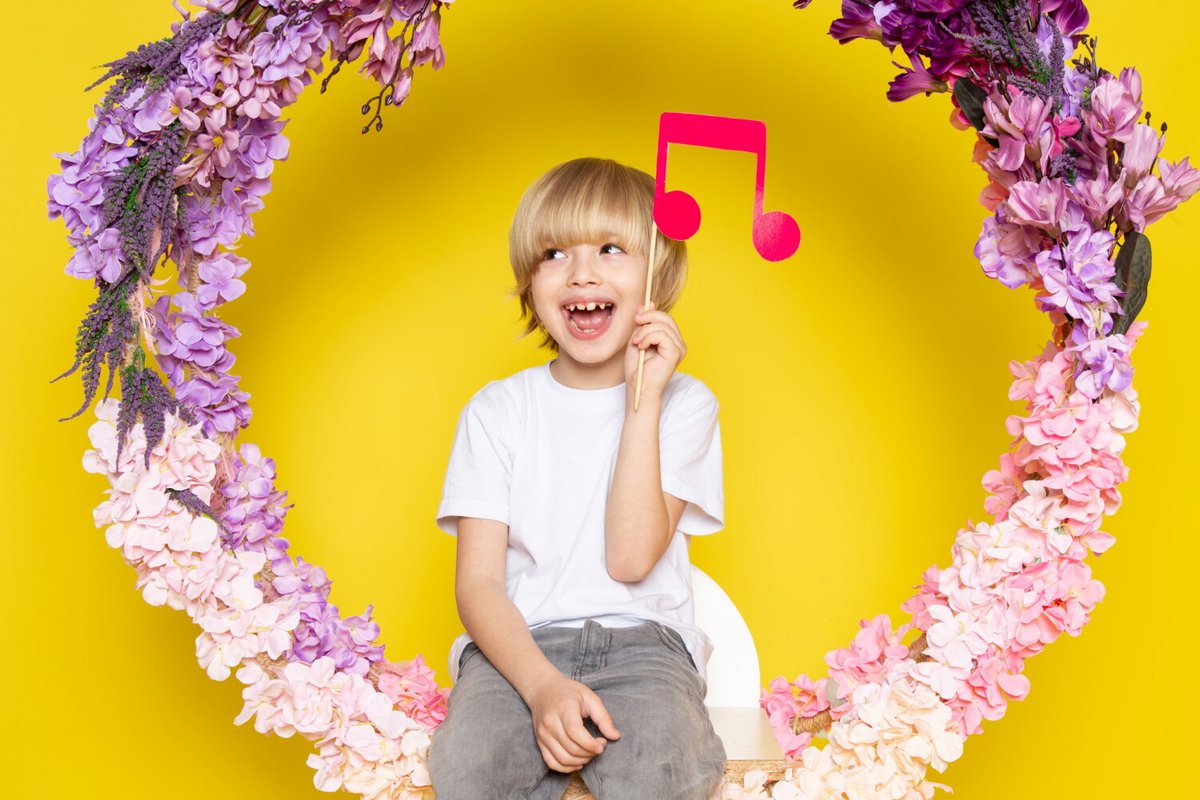 Мальчик на фоне цветочной арки держит в руке картонную ноту