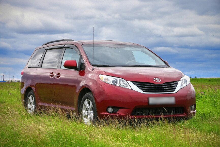 Бордовая Toyota Sienna на фоне зелёной травы