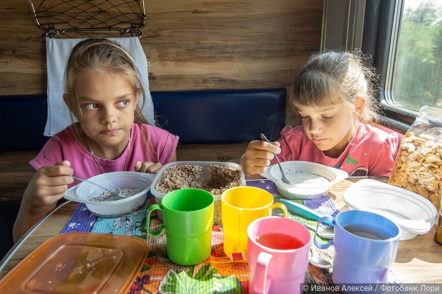 Две девочки обедают в поезде из пластиковой одноразовой посуды